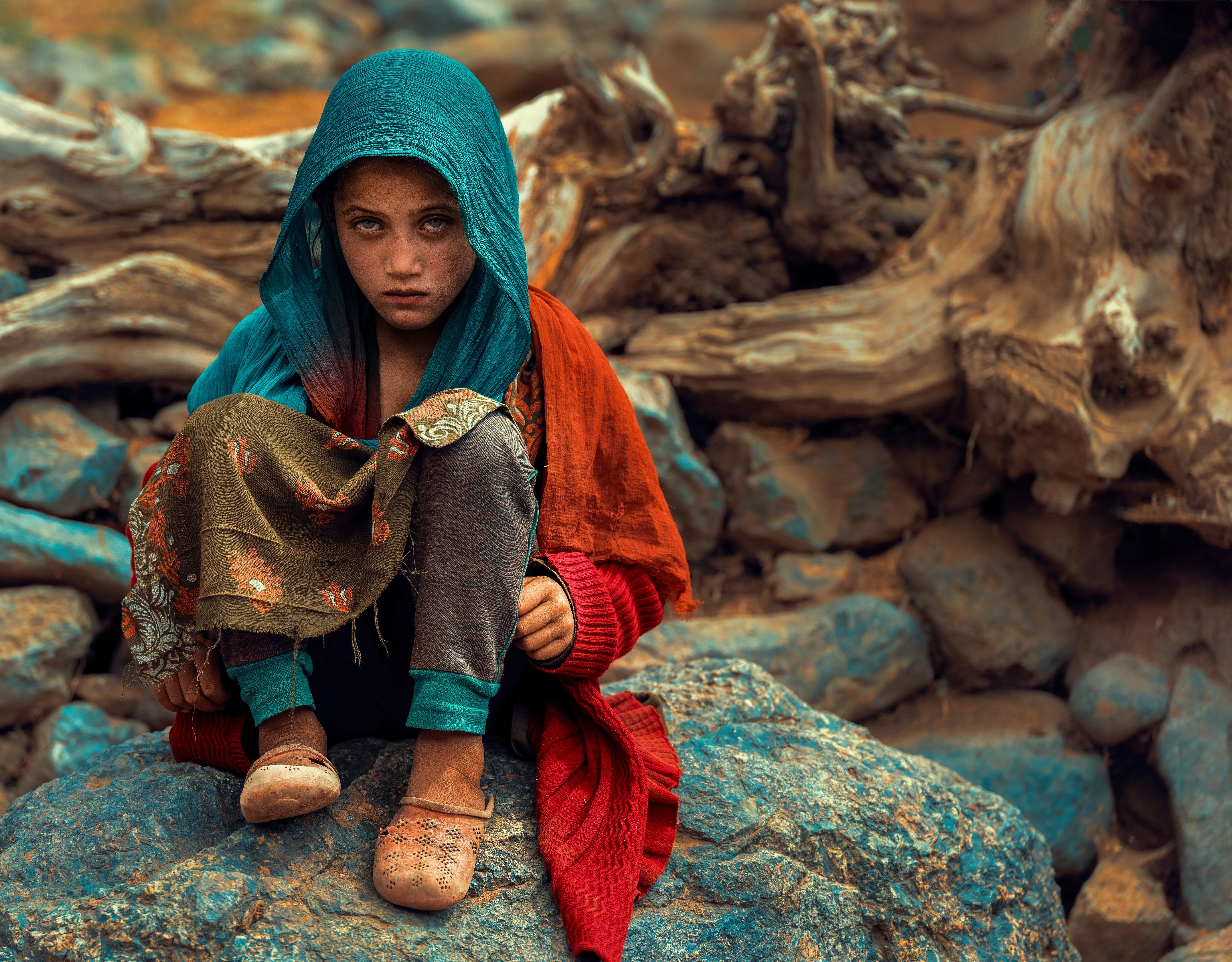 Ein afghanisches Mädchen sitzt auf einem Felsen