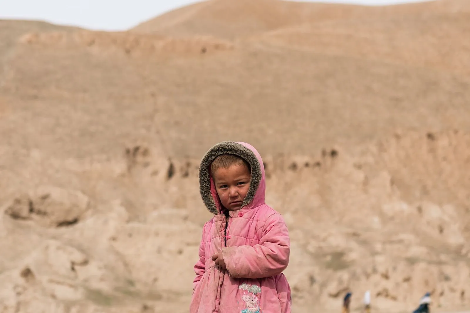 Ein Mädchen steht in einer kargen Landschaft in Afghanistan